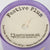 Candle labeled 'Festive Plum' by Questionables with purple lid and beige label.