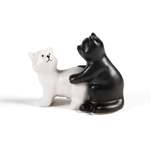 Black and white ceramic cat figurines in a suggestive position on a white background.