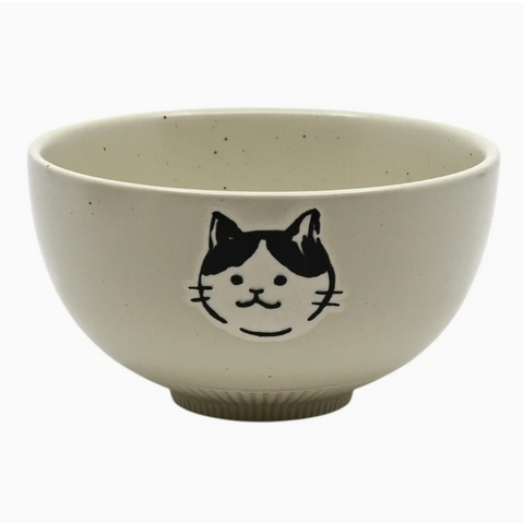 An off-white ceramic bowl with black speckles and a black cat face illustration on the front, set against a plain white background.