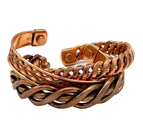 A stack of copper bracelets in three styles, including braided and twisted patterns, shown on a plain white background.