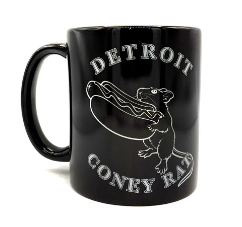A glossy black ceramic mug featuring a white graphic of a rat holding a hot dog, with the words 'DETROIT' and 'CONEY RAT' printed in a distressed white font.