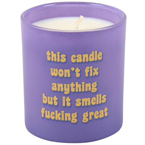 Purple glass candle with yellow text on a white background. Text on candle reads "This candle wont fix anything but it smells fucking great."