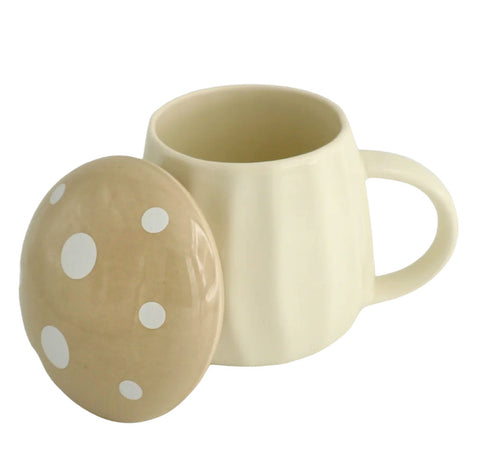 A cream-colored ceramic mug with a matching lid featuring white polka dots, set against a plain white background.