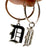 Two silver hoop earrings and a cutout gothic letter 'D' charm, one black and one silver, held by a hand against a white background.