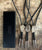 Three bolo ties with stone pendants on braided cords next to a black box with branding on a wooden surface.
